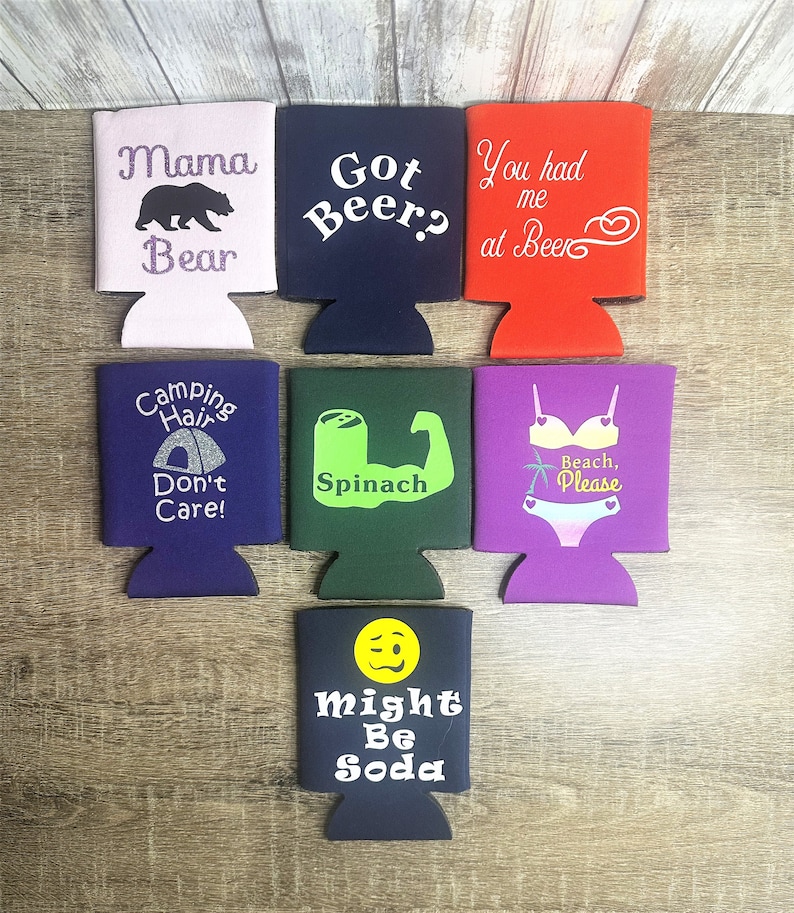 Pode incluir: Conjunto de 7 frios de lata coloridos com v&aacute;rios ditos e desenhos humor&iacute;sticos. Os ditos incluem "Mama Bear", "Got Beer?", "You had me at Beer", "Camping Hair Don't Care", "Spinach", "Beach, Please", e "Might Be Soda".