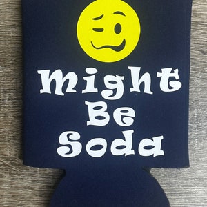 Pode incluir: Um refrigerador de latas azul com um rosto sorridente branco piscando e o texto "might be soda".