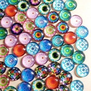 Könnte beinhalten: Sortiment an bunten Glascabochons mit komplizierten Mustern und Designs. Die Cabochons sind rund und haben eine glänzende Oberfläche. Sie sind perfekt zum Basteln und für die Schmuckherstellung.