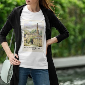 May include: A white t-shirt with a graphic print of a watercolor illustration of a historic mill building. The text "Marlborough Mills" is printed below the image.