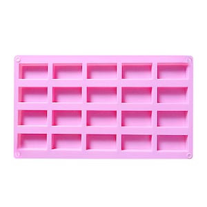 May include: A rectangular, light pink silicone mold with 24 rectangular cavities. The mold has rounded corners and small circular holes on each end. The cavities are evenly spaced and appear to be for making small bars or shapes.