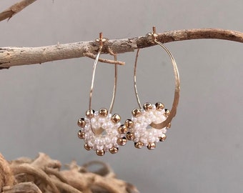 Delicate and festive hammered gold-filled hoop earring with threaded white  and gold pendant, snowflake-shaped pendant, white flower