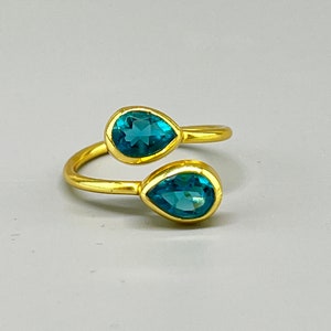 Puede incluir: Un anillo de oro con dos piedras azules en forma de lágrima.