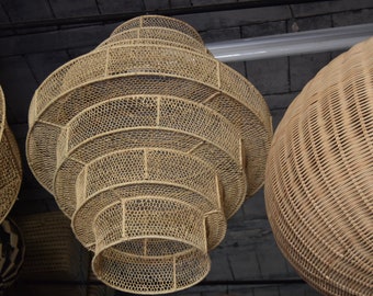 May include: A set of three woven pendant lights, each with a layered, circular design. The lights are made from natural materials and have a warm, rustic aesthetic.