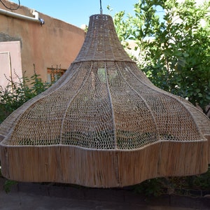May include: A large, woven, light brown lampshade hangs from the ceiling. The lampshade is made of natural materials and has a unique, organic shape.