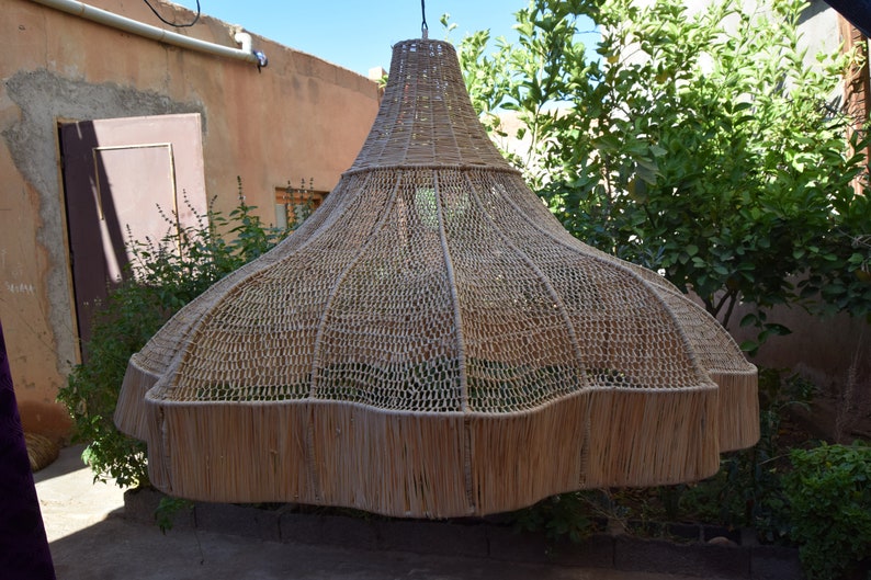 May include: A large, woven, light brown lampshade hangs from the ceiling. The lampshade is made of natural materials and has a unique, organic shape.
