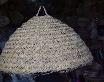 May include: A large, round, woven lampshade made of natural materials. The lampshade is light brown and has a woven pattern.