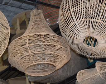 May include: A collection of woven wicker pendant lights, each with a unique shape and pattern. The lights are hanging from the ceiling and are illuminated, casting a warm glow.