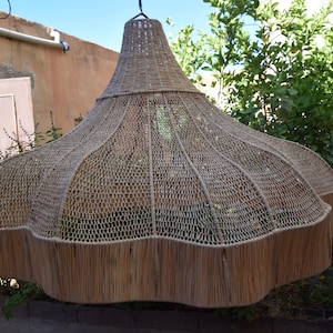 May include: A large, woven, light brown lampshade hangs from the ceiling. The lampshade is made of natural materials and has a unique, organic shape.