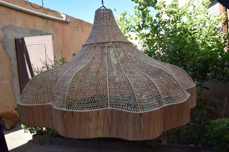 May include: A large, woven, light brown lampshade hangs from the ceiling. The lampshade is made of natural materials and has a unique, organic shape.