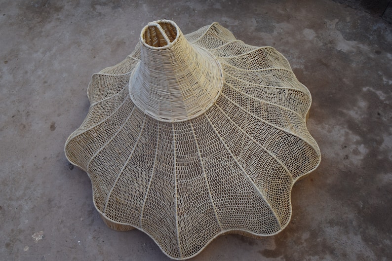 May include: A large, white, woven lampshade with a scalloped edge. The lampshade is made of a natural material, possibly rattan or bamboo.