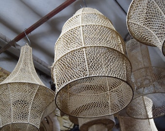 May include: A group of woven, beige, lampshades hanging from the ceiling. The lampshades are made of a natural material, possibly rattan or bamboo, and have a delicate, intricate pattern.
