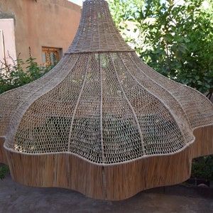 May include: A large, woven, light brown lampshade with a scalloped edge. The lampshade is made of natural materials and has a unique, organic shape.