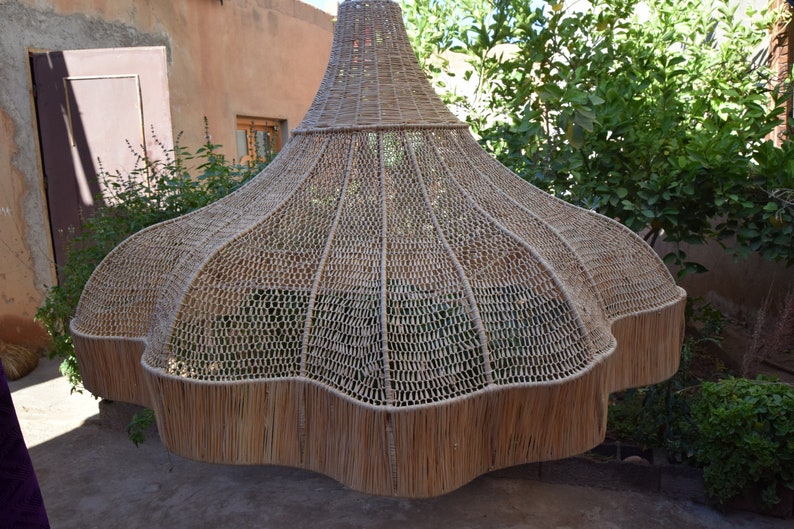 May include: A large, woven, light brown lampshade with a scalloped edge. The lampshade is made of natural materials and has a unique, organic shape.