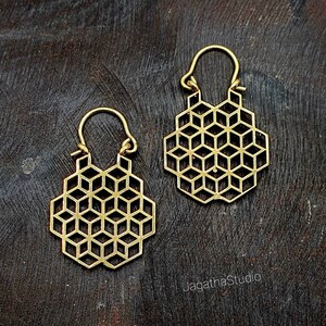 Könnte beinhalten: Ein Paar goldene geometrische Creolen mit einem sechseckigen Muster. Die Ohrringe sind aus Metall und haben ein schlichtes, modernes Design.