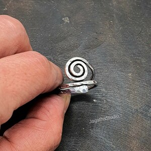 May include: Silver ring with a hammered finish and a spiral design.