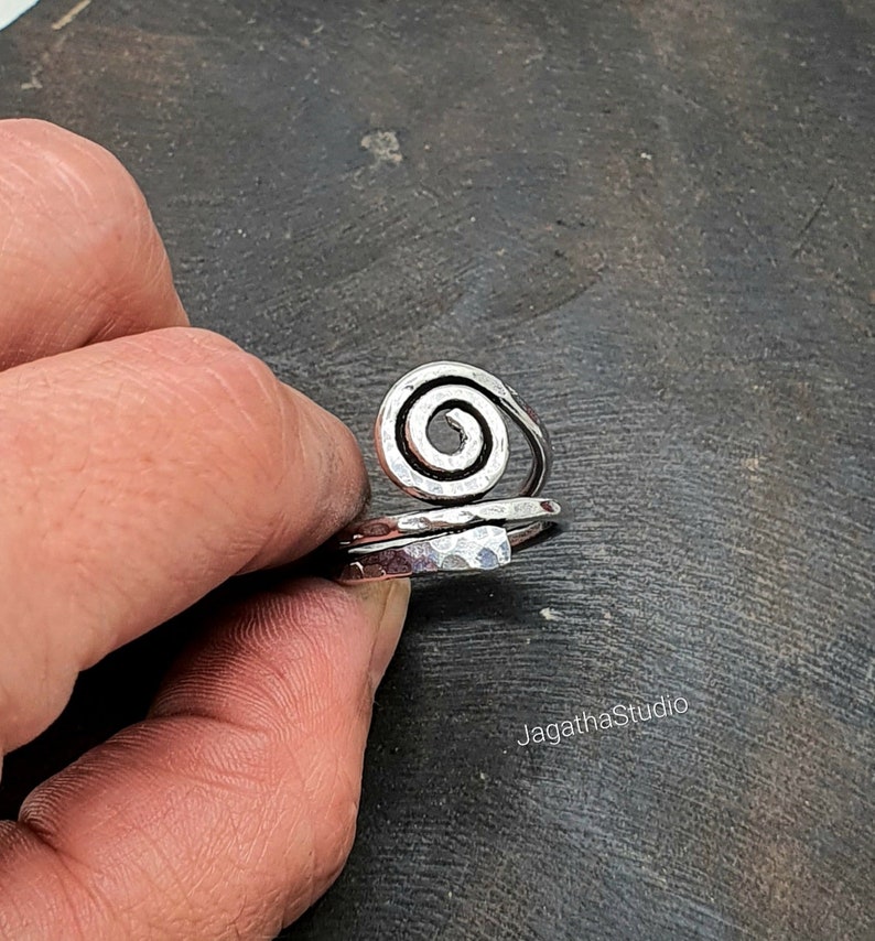 May include: Silver ring with a hammered finish and a spiral design.