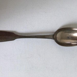 May include: A silver spoon with a rounded bowl and a simple, elegant handle.