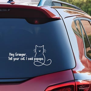 Puede incluir: Calcomanía de coche de vinilo blanco con un contorno de gato y el texto "Hey Granger. Dile a tu gato que dije pspspsps." La calcomanía está en la ventana trasera de un vehículo rojo.
