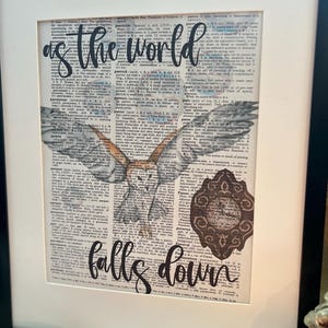May include: A framed print with a vintage dictionary page background featuring a white owl with outstretched wings. The text "as the world falls down" is written in black cursive script over the owl.
