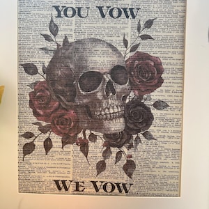 May include: A black and white skull with red roses printed on a vintage dictionary page. The text on the page reads "I vow you vow we vow".