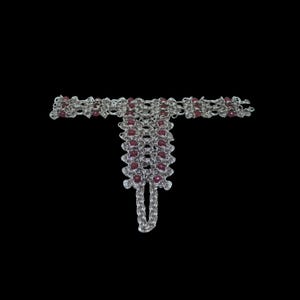May include: A silver-colored hand chain bracelet with a finger ring. The bracelet features a chainmail design with small, round, red beads. The background is solid black.