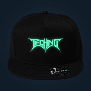 Może przedstawiać: Czarna czapka typu snapback z napisem TECHNO nadrukowanym stylizowaną, ostro zakończoną miętową czcionką na przednich panelach. Okrągła naklejka na płaskim daszku zawiera tekst The Original Snapback One Size Fits All.