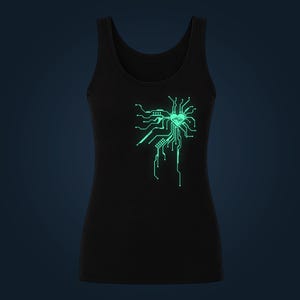 Könnte beinhalten: Ein schwarzes Tanktop mit einer leuchtend hellgrünen Grafik auf der Brust. Das Design zeigt eine Herzform, die in ein komplexes Leiterplattenmuster mit Linien und Knoten integriert ist, das an das Layout einer digitalen Hauptplatine erinnert.