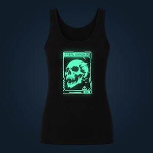 May include: A black tank top featuring a glowing light green graphic of a skull inside a digital window. The text FATAL ERROR is printed at the top of the box, with an exclamation point warning icon and an OK button at the bottom of the design.