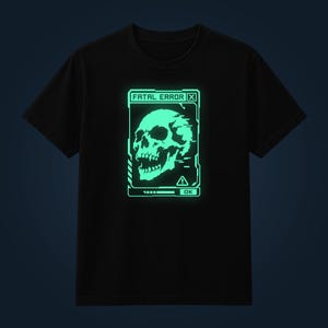 Op de afbeelding: Een zwart t-shirt met korte mouwen en een lichtgevende mintgroene afbeelding van een menselijke schedel in een digitaal computervenster. De tekst FATAL ERROR staat bovenaan, met een OK-knop en een waarschuwingspictogram onderaan.