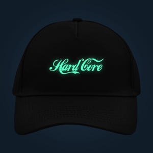 Könnte beinhalten: Eine schwarze Baseballkappe mit dem Schriftzug Hard Core in einer leuchtend hellgrünen Schreibschrift auf der Vorderseite. Das Design enthält einen kleinen Stern über dem Buchstaben o. Die Kappe hat eine strukturierte Krone und einen gebogenen Schirm.