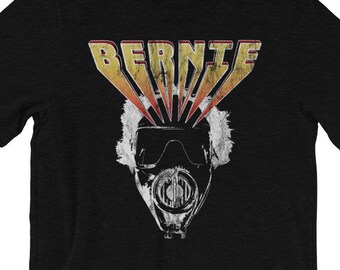 May include: Black t-shirt with a vintage-style graphic of Bernie Sanders wearing a gas mask with the word "BERNIE" in yellow and orange letters above his head.