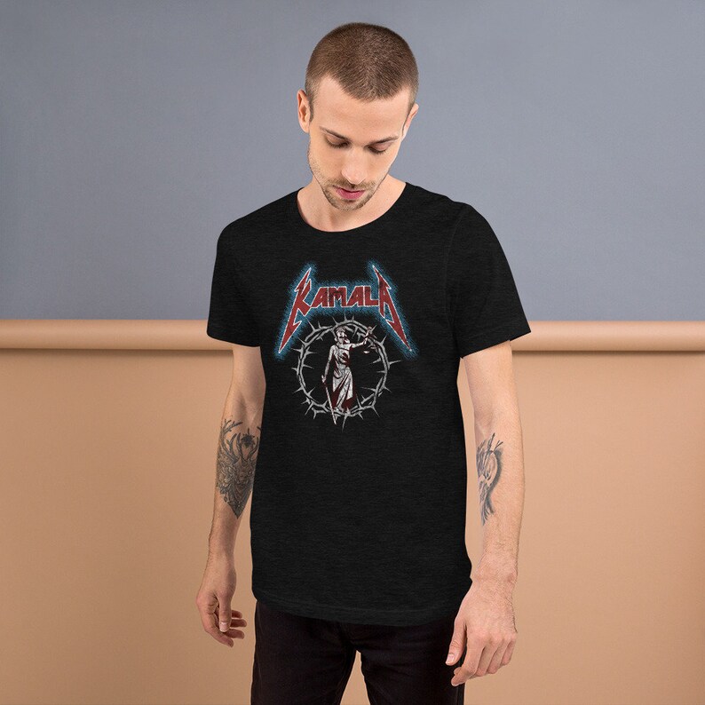 May include: A black t-shirt with a graphic print of a woman holding a sword in a circle of thorns. The text "KAMALA" is printed in red above the graphic.