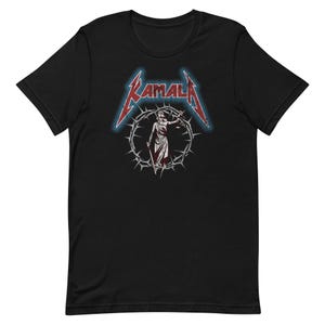 May include: Black t-shirt with a red and blue graphic of a woman in a robe holding a scale of justice. The graphic is surrounded by a crown of thorns and the word "KAMALA" is written in a metal font.