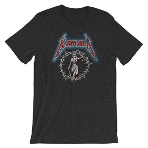 May include: A dark heather grey t-shirt with a red and white graphic of a woman holding scales of justice. The graphic is surrounded by a circle of thorns and the text "KAMALA" is above the graphic.