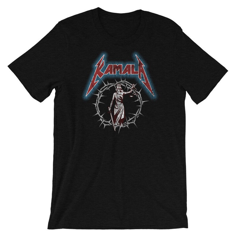 May include: Black t-shirt with a red and white graphic of a figure holding scales of justice in a crown of thorns. The text "KAMALA" is above the figure in a stylized font.