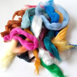 May include: A pile of colorful wool roving in shades of blue, green, pink, yellow, orange, brown, and white. The wool is soft and fluffy, perfect for felting or spinning.
