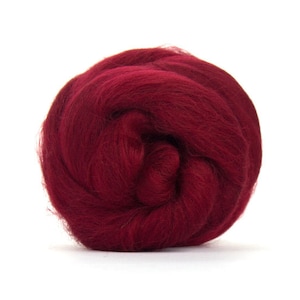 Puede incluir: Una bola de vellón de lana de color rojo oscuro, un tipo de fibra que se utiliza para el fieltro y el hilado.