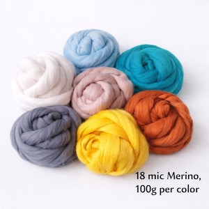 May include: A collection of eight colorful balls of Merino wool in shades of white, light blue, teal, orange, yellow, gray, and pink. The text "18 mic Merino, 100g per color" is visible. These wool balls are ideal for various crafting projects.