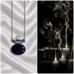 May include: A silver-toned necklace featuring a large, oval-shaped dark blue sandstone pendant with glittery inclusions, topped with a smaller, round, translucent white moonstone, all suspended from a delicate silver-toned metal chain.