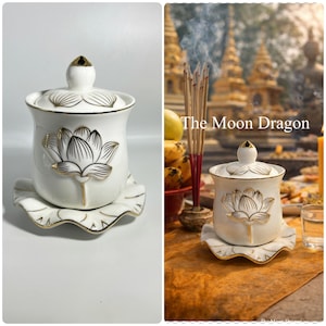 May include: A white ceramic lidded jar with a gold-trimmed lotus flower design on the body and lid, resting on a matching scalloped saucer. The piece features delicate gold outlines and a pointed finial on the lid, presenting a clean, elegant aesthetic.