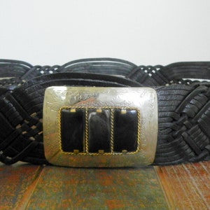 May include: A black leather braided belt with a silver buckle featuring three black stones.