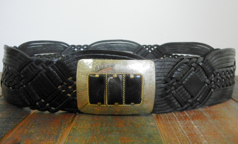 May include: A black leather braided belt with a silver buckle featuring three black stones.