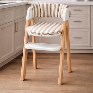 May include: A modern high chair with a light wood frame and white accents. The seat and backrest feature a beige and white striped pattern. The chair has a footrest and is designed for young children.