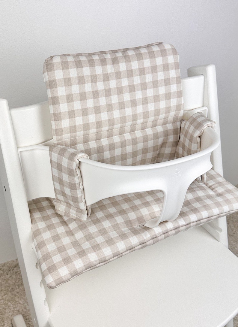 Wipeable high chair cushion in neutral design, fitted on Stokke Tripp Trapp high chair, providing extra comfort and easy-to-clean surface for babies and toddlers.