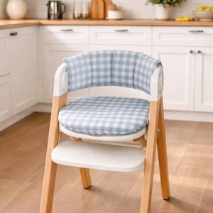 May include: A high chair with a light wood frame, white accents, and a blue and white gingham patterned cushion and backrest. The chair has a white tray and is designed for a baby or toddler.