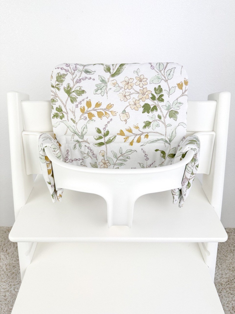 Puede incluir: Silla alta blanca con un coj&iacute;n estampado floral. El coj&iacute;n tiene un dise&ntilde;o floral de color verde claro, amarillo y morado.