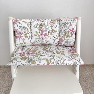 Puede incluir: Silla alta blanca con un coj&iacute;n de estampado floral. El coj&iacute;n est&aacute; hecho de tela con flores rosas y verdes sobre un fondo blanco.
