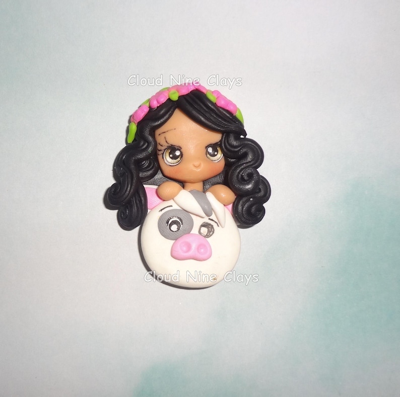 May include: A handcrafted polymer clay figurine featuring a dark-haired girl with a floral headband, emerging from a white pig with a pink snout. The figurine has large, expressive eyes. The text "Cloud Nine Clays" is visible.