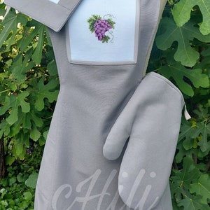 Puede incluir: Delantal de cocina gris con un diseño de uva bordado en blanco, un posavasos a juego y un guante de horno gris.